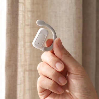 One translator earbud held between two fingers, showing how small it is