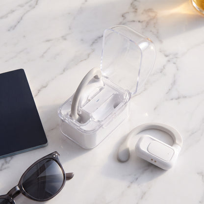 Earbuds and open case on marble beside a passport and sunglasses
