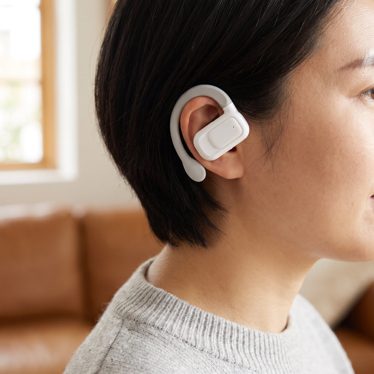 Woman wearing one translator earbud, the soft hook resting over her ear